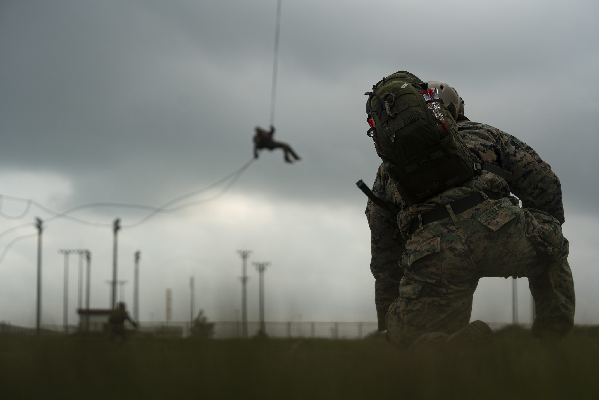 A U.S. Navy corpsman with Expeditionary Operations Training Group, III Marine Expeditionary Force Information Group, supervises students performing helicopter rope suspension technique training at the parade deck on Camp Hansen, Okinawa, Japan, Aug. 14, 2019.
