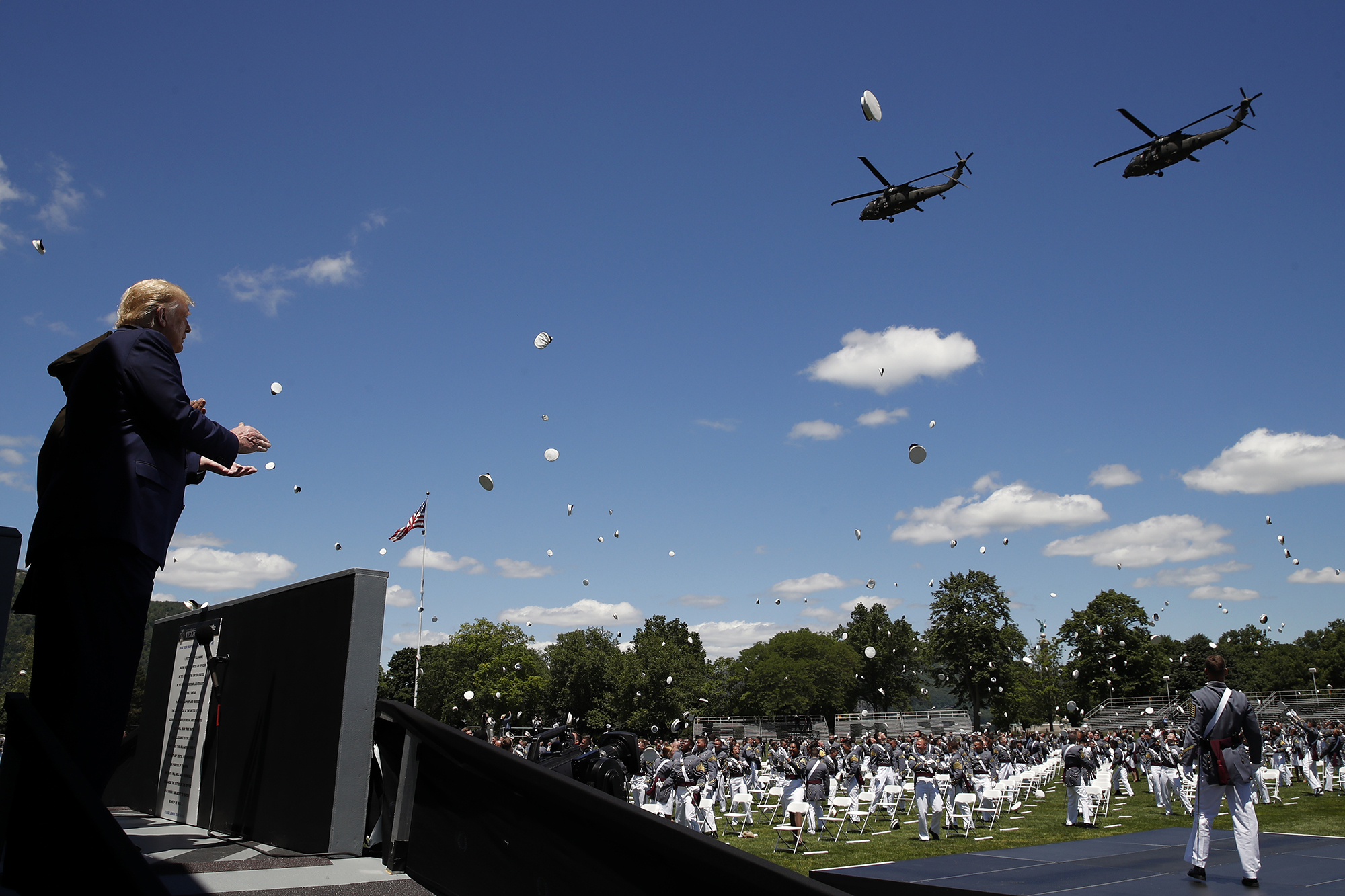 President Donald Trump applauds as Army helicopters fly over and West Point cadets toss their caps into the air at the end of commencement ceremonies on the parade field, at the United States Military Academy in West Point, N.Y., Saturday, June 13, 2020.