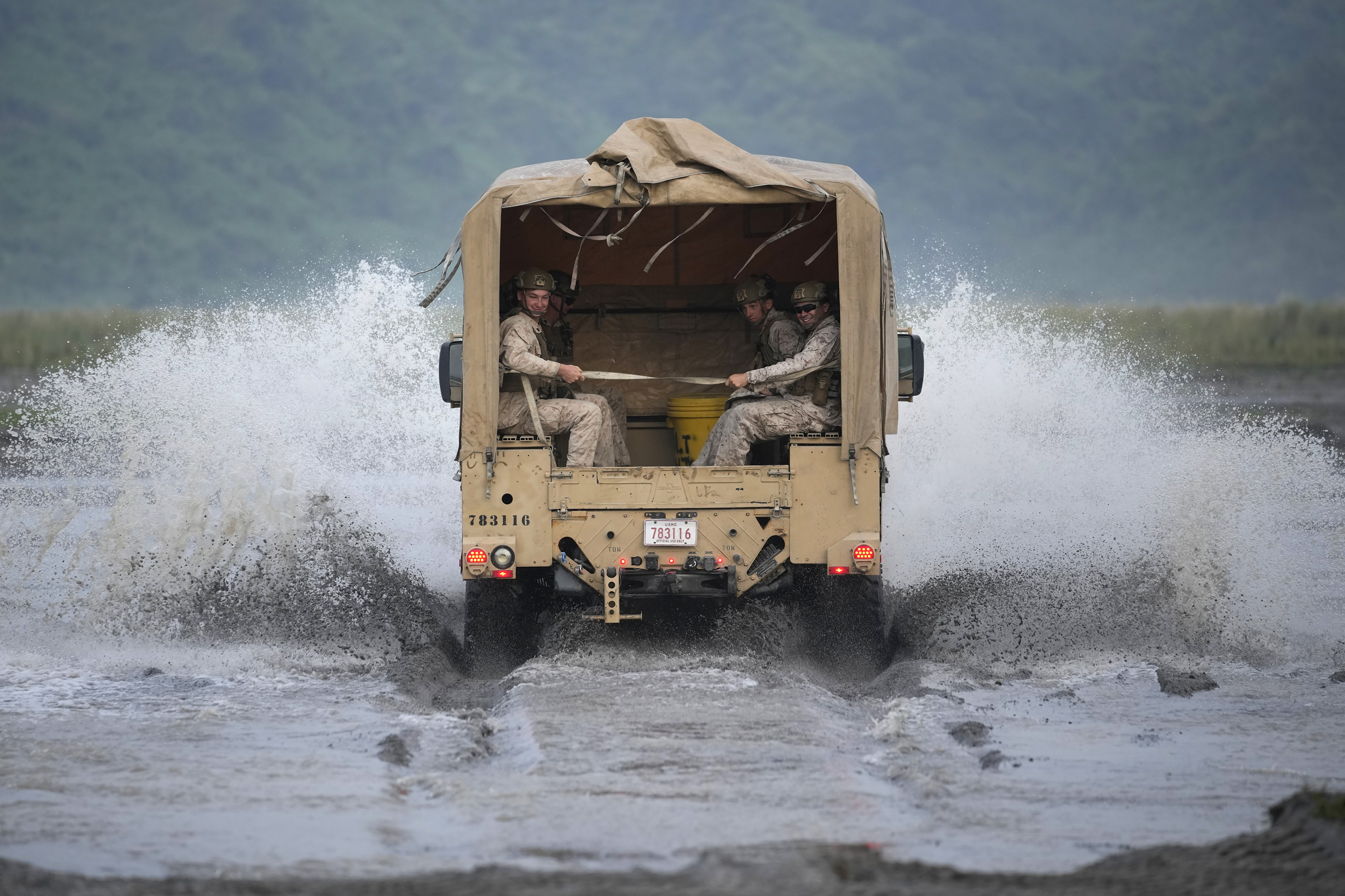 American Marines ride their vehicle across a stream during annual combat drills between the Philippine Marine Corps and U.S. Marine Corps in Capas, Tarlac province, northern Philippines, Thursday, Oct. 13, 2022.