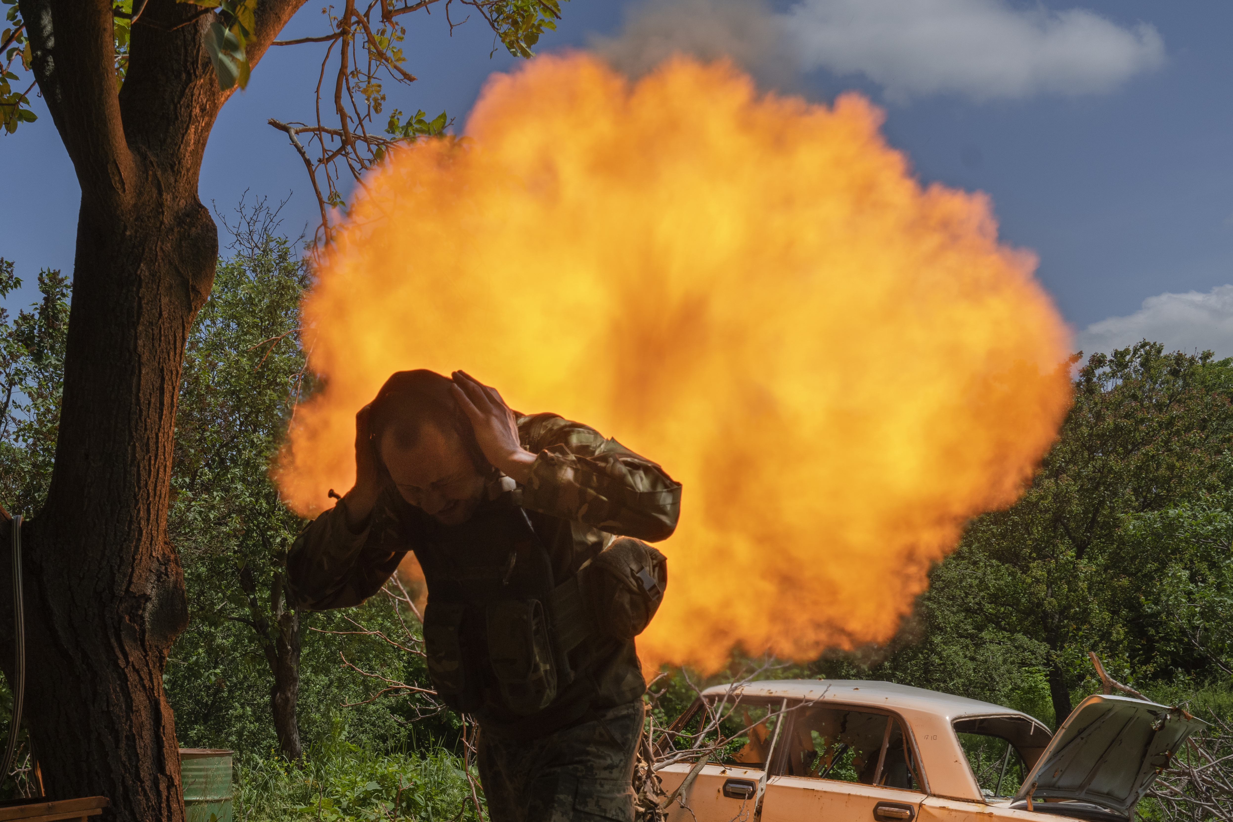 A Ukrainian soldier covers his ears while firing a mortar at Russian positions on the frontline near Bakhmut, Donetsk region, Ukraine, Monday, May 29, 2023.